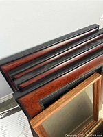 Photo showing several stacked dark brown and black-trimmed wooden picture frames