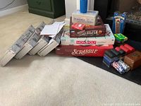 Overview of game boxes stacked on carpeted floor beside poker chips and card decks, metal cases visible nearby.