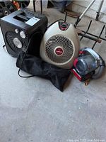 Overview photo showing two Vornado heaters, a Black+Decker vacuum, fireplace grate, and gas burner in garage setting