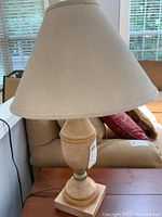 Photo showing one of the matching table lamps with beige fabric shade and wooden base with accent rings.