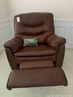 Front view of recliner with footrest partially extended and pillow on seat