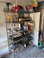Full view of silver wire shelving unit with 5 shelves holding various household items including cookware and boxes.
