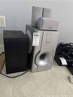 Full setup showing LG black wireless subwoofer unit and TEAC silver subwoofer with three satellite speakers on top
