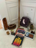 Full lot displayed on carpet corner showing bat, gloves, memorabilia, magazines, bags, and other items
