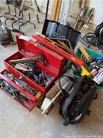Overview of two red metal toolboxes filled with various hand tools and accessories, partially open showing contents