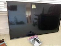 Front view of the 60-inch LG LED TV leaning against a wall, showing the screen and bezel