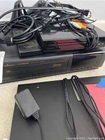 Fisher VCR player underneath a black DVD player, with assorted cables on top and a visible power adapter.