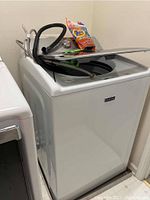 Front and side view of white Maytag Bravos XL washer with hoses and detergent on top