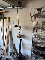 Echo gas weed trimmer hanging on wall with garden tools nearby in garage
