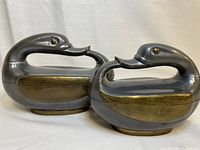 Two metal swan-shaped dishes with brass and silver-tone finish side by side, showing size difference