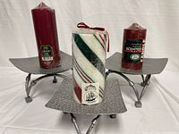 Front view of three metal candle holders with three pillar candles (two solid burgundy and one striped).