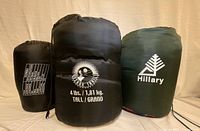 Three sleeping bags in sacks, front view showing logos and weights