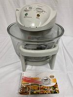 Full view of the convection oven with glass bowl, white plastic stand, control unit on top, and Flavor Wave Turbo recipe book in front