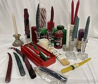 Photo showing a large assortment of taper candles including beeswax, twisted, and colored tapers along with scented pillar candles and various pottery and glass candle holders.