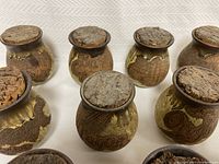 View of the collection of eleven pottery spice jars showing the varied glaze and cork lids with spice names inscribed.