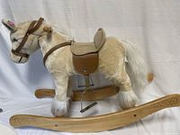 Full side view of plush rocking horse with wooden rockers on white backdrop.