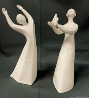 Front and side view of two white porcelain figurines titled 'Peace' and 'Awakening', showing their full height and posture.