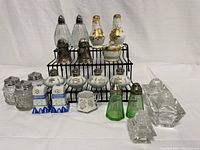 Full lot, includes nine sets of salt and pepper shakers and three small containers arranged on a wire stand and table.