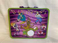 Front view of Scooby Doo lunchbox with band theme and purple handle.