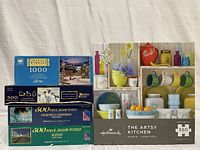Group of five jigsaw puzzle boxes showing titles, piece counts, and images associated with each puzzle