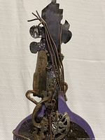 Full view of the abstract violin sculpture with twisted metal rods and wooden painted body.
