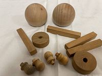 Wooden toy parts including two round balls, dowels, and carved pieces laid out for detail.