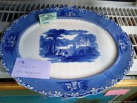Full view of the large oval blue transferware platter with floral border and central scenic design showing the entire plate.
