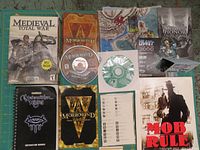 Overview of the lot showing multiple game cases, manuals, discs, and maps arranged on a green grid mat, highlighting the range of titles and media types.