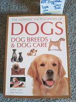 Front cover of The Ultimate Encyclopedia of Dogs book showing a large golden retriever image and smaller images of other dog breeds with title text.