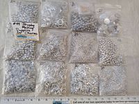 Photo showing all 12 bags of various silver jewelry making supplies including beads and charms.