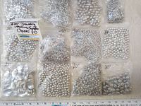All 12 packages of silver-tone jewelry making supplies laid out on table