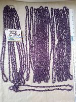 Multiple long strands of light purple amethyst chip beads arranged next to a ruler showing size scale, with a label indicating 'Glass Beads Lot Strands Natural Amethyst'.