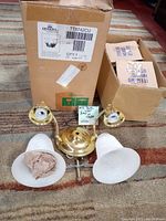 Full view of the Quoizel wall lamp with two shades laid in front of two original boxes, showing the fixture and lampshades with partial protective wrap.