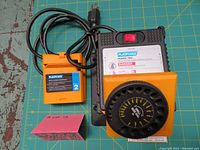 Main Plasplugs power unit with attached yellow Module 3 drill sharpener and next to it Module 2 attachment and power cord coiled.