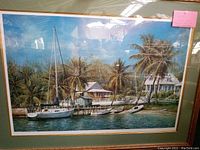 full front view of framed print showing sailboat docked at wooden pier with cottage and palm trees