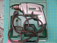 Image of the Skil reversing drive drill inside its green molded carrying case, showing the power cord wrapped inside the case.