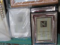 Close-up of two silver plated 2x3 inch photo frames showing decorative edges with original inserts