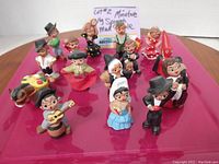 Full view of 15 hand-painted vintage Spanish mud clay miniatures showing various traditional figures in colorful costumes.