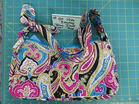 Full view of the vintage Vera Bradley handbag showing the blue, pink, black paisley floral pattern and the 9 inch short strap with tie knot.