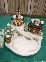 Photo of Goebel Hummelscape musical Christmas home figurine showing church, house, trees, and snow detail.