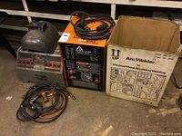 Overview of two welder units, helmet, cables and rod box