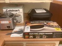 Photo showing all three appliances including the Cuisinart rice cooker with box, Salton electric crepe maker box and batter dish, Hamilton Beach skillet/griddle.