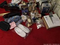 Overview photo showing assortment of bath and personal care items including slippers, makeup bags, boxed clothes shaver, mirrored tray, bath salts, and towel rack.