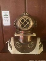 Front view of brass dive helmet lamp showing lattice window and base details.