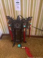 Front and full view of black Chinese lantern decorated with red tassels and turquoise beads, ornate dragon carvings at corners, and electrical cord visible at top.