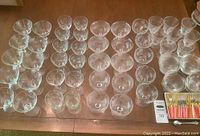 Wide view of all glasses neatly arranged on a wooden table with cocktail forks on the side.