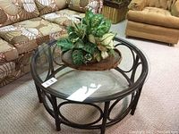 Top view of round bamboo frame coffee table with clear glass top and decorative plant.