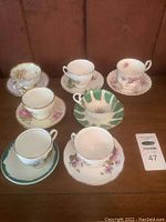 Overview photo of 6 teacups and matching saucers arranged on table showing various floral designs.