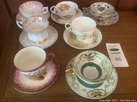 Overview of six porcelain teacups with saucers featuring various floral designs and gold accents.