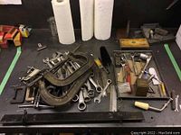 Full lot of mixed hand tools scattered on a surface showing clamps, wrenches, sockets, punches, and other tools.